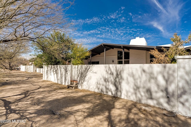 view of home's exterior with a chimney, fence, and stucco siding