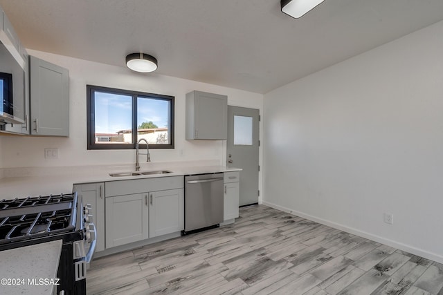 kitchen with gray cabinetry, light wood-type flooring, sink, and appliances with stainless steel finishes