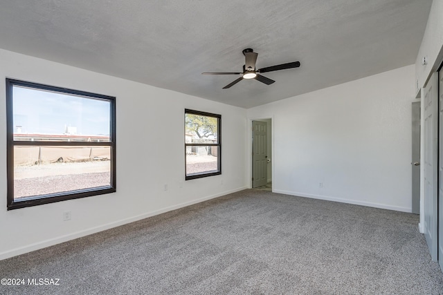 unfurnished room with a textured ceiling, carpet floors, and ceiling fan