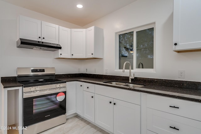 kitchen with white cabinetry, stainless steel range, dark stone counters, and sink