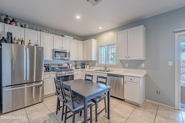 kitchen with white cabinets, appliances with stainless steel finishes, light tile patterned floors, and sink