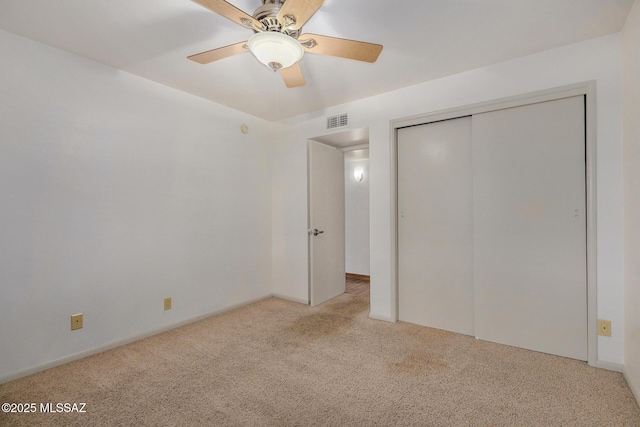 unfurnished bedroom featuring ceiling fan, a closet, and light carpet