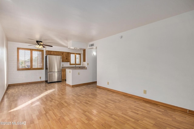 unfurnished living room featuring light wood-type flooring and ceiling fan