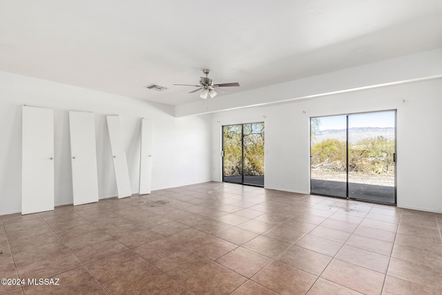 tiled empty room with a wealth of natural light and ceiling fan