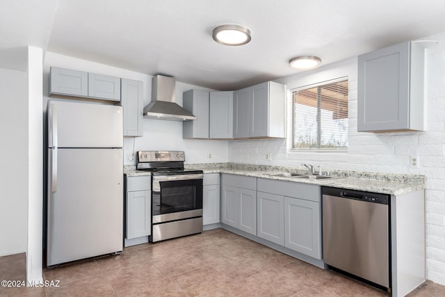 kitchen featuring gray cabinetry, wall chimney exhaust hood, sink, and appliances with stainless steel finishes