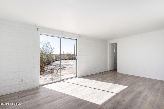 spare room featuring light hardwood / wood-style floors and brick wall