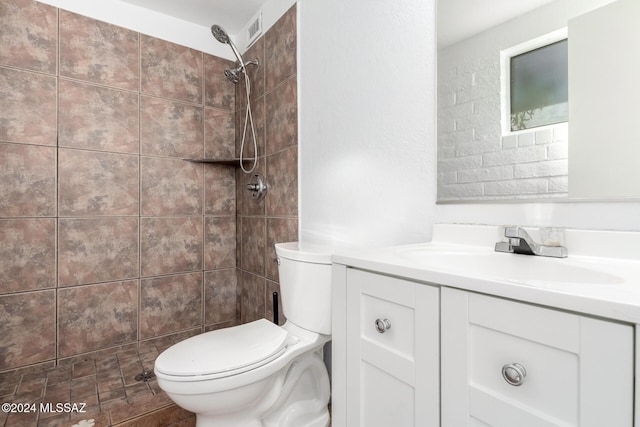 bathroom featuring a tile shower, vanity, and toilet