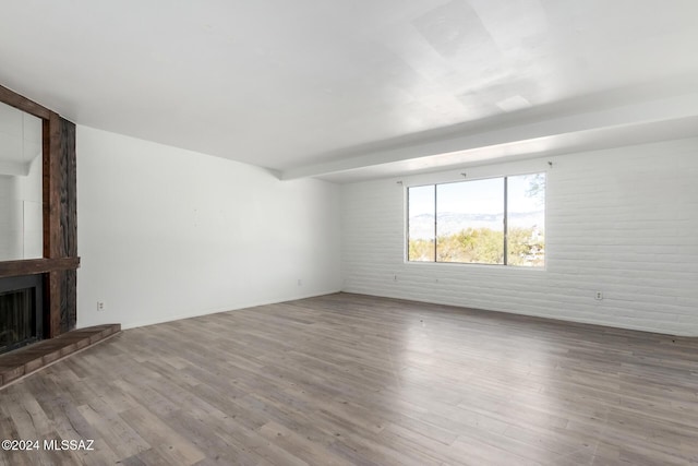 unfurnished living room featuring light wood-type flooring, a fireplace, and brick wall