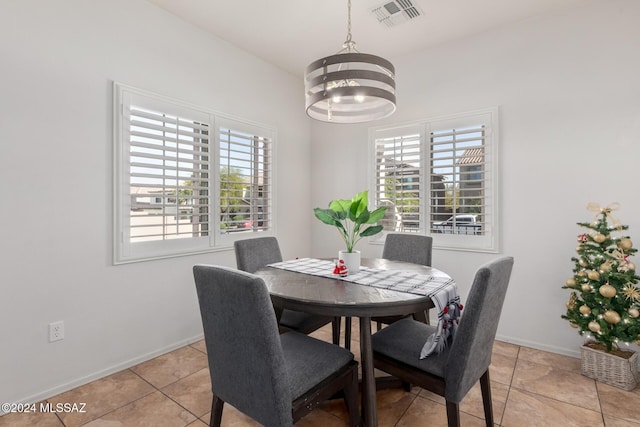 kitchen featuring appliances with stainless steel finishes, pendant lighting, an inviting chandelier, dark stone countertops, and light tile patterned flooring