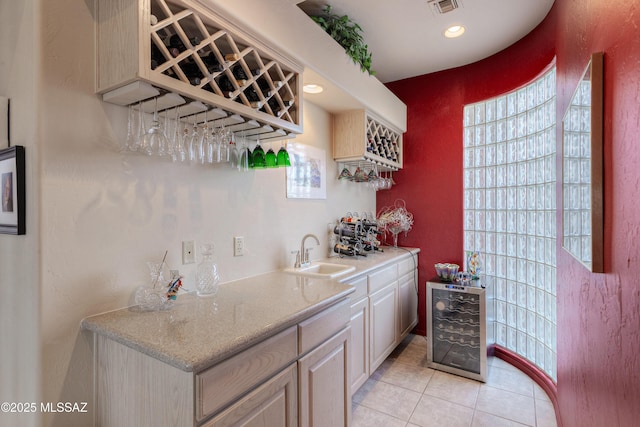 bar featuring sink, light tile patterned floors, and beverage cooler