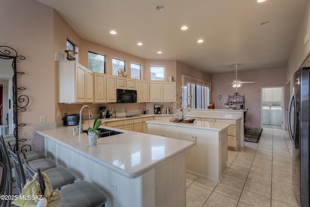 kitchen featuring kitchen peninsula, a kitchen breakfast bar, washing machine and clothes dryer, and black appliances