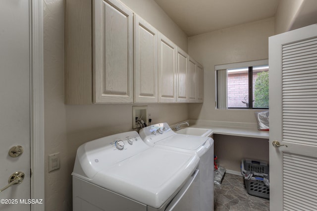 clothes washing area with washing machine and dryer, sink, and cabinets