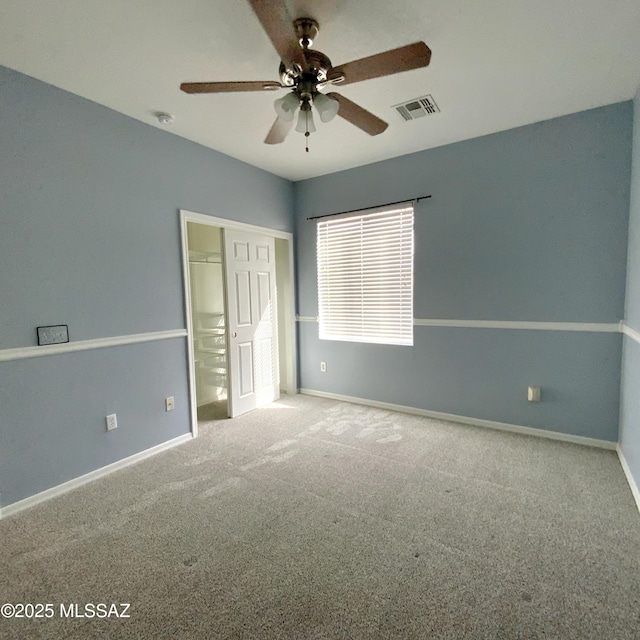 unfurnished bedroom featuring a walk in closet, carpet flooring, ceiling fan, and a closet