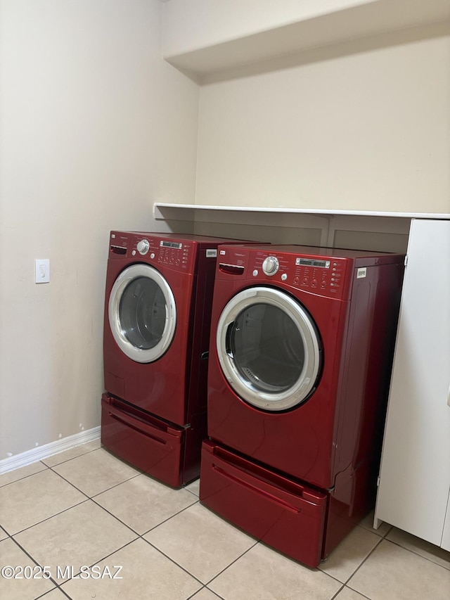 clothes washing area with washing machine and dryer and light tile patterned floors