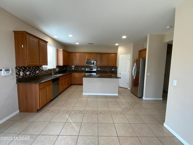 kitchen with stainless steel appliances, sink, light tile patterned floors, and dark stone counters