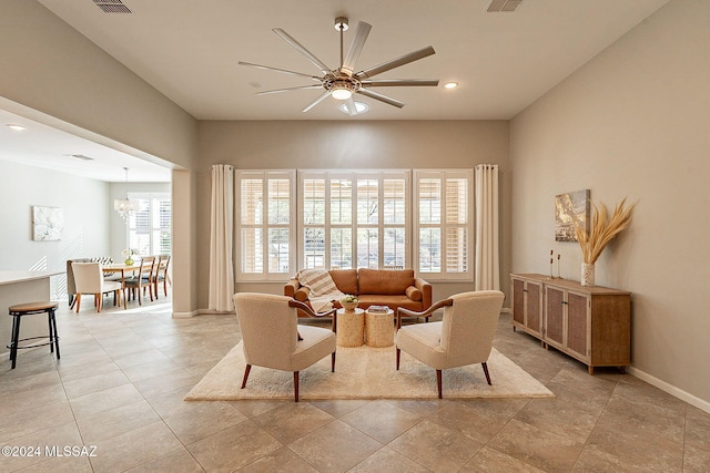 tiled living room featuring ceiling fan with notable chandelier