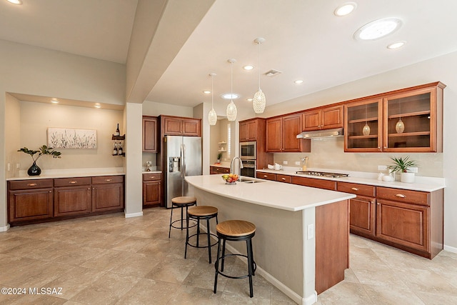 kitchen featuring pendant lighting, a breakfast bar, a center island with sink, sink, and appliances with stainless steel finishes