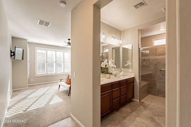 bathroom featuring tile patterned flooring, plenty of natural light, a tile shower, and vanity