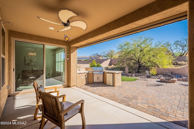 view of patio featuring a grill, ceiling fan, exterior kitchen, and an outdoor fire pit