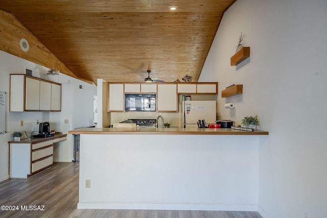 kitchen with kitchen peninsula, stove, vaulted ceiling, and white refrigerator