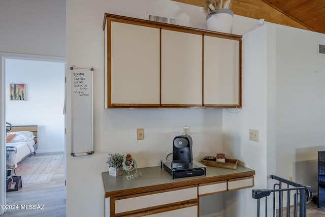 interior space with built in desk, lofted ceiling, and light hardwood / wood-style floors