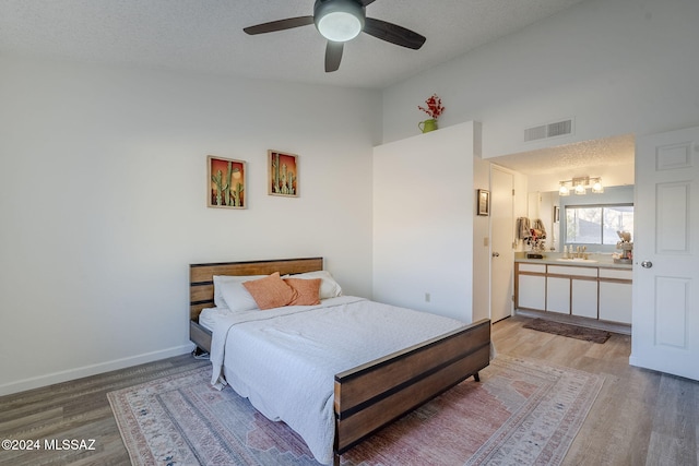 bedroom with ceiling fan, sink, wood-type flooring, and a textured ceiling