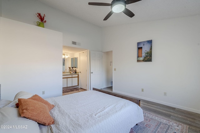 bedroom with wood-type flooring, connected bathroom, ceiling fan, and a high ceiling