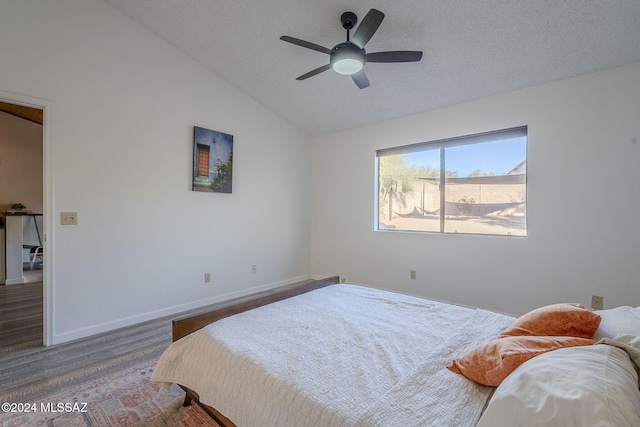 bedroom featuring hardwood / wood-style floors, a textured ceiling, vaulted ceiling, and ceiling fan