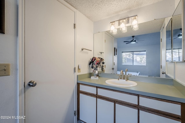 bathroom with ceiling fan, vanity, and a textured ceiling