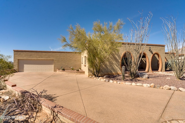 pueblo-style house featuring a garage and concrete driveway