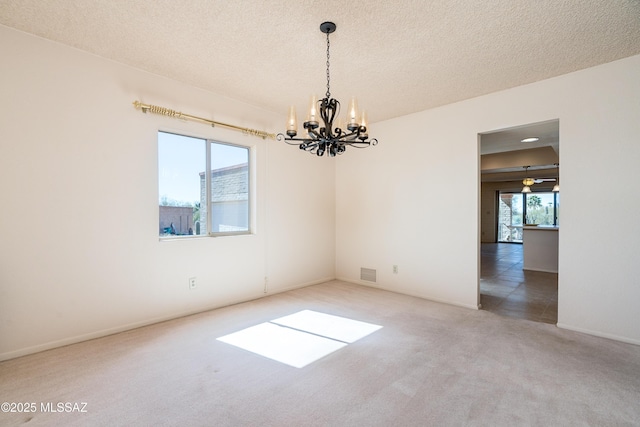 carpeted spare room featuring a healthy amount of sunlight, visible vents, and a textured ceiling