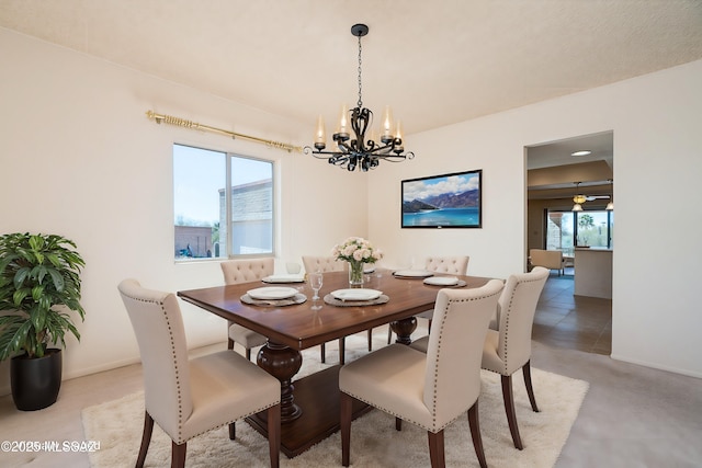 dining room featuring concrete flooring, a notable chandelier, and baseboards