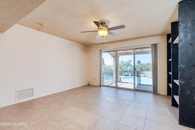 unfurnished room featuring a textured ceiling, light tile patterned flooring, visible vents, and a ceiling fan