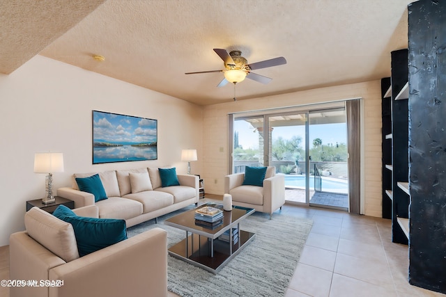 living area featuring light tile patterned flooring, ceiling fan, and a textured ceiling