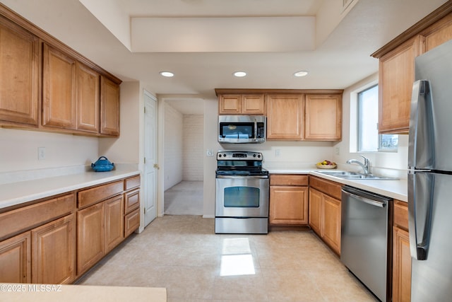 kitchen featuring recessed lighting, stainless steel appliances, a sink, light countertops, and a raised ceiling