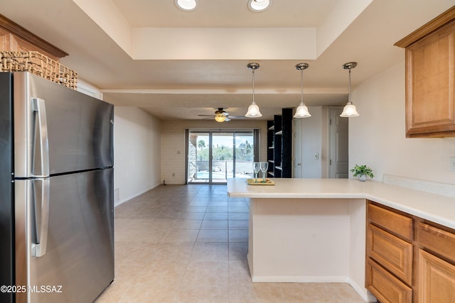 kitchen featuring open floor plan, decorative light fixtures, a peninsula, freestanding refrigerator, and light countertops