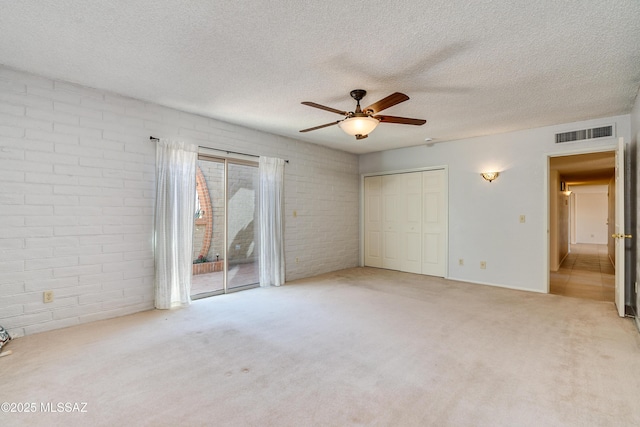 unfurnished bedroom featuring light carpet, access to outside, visible vents, and a textured ceiling