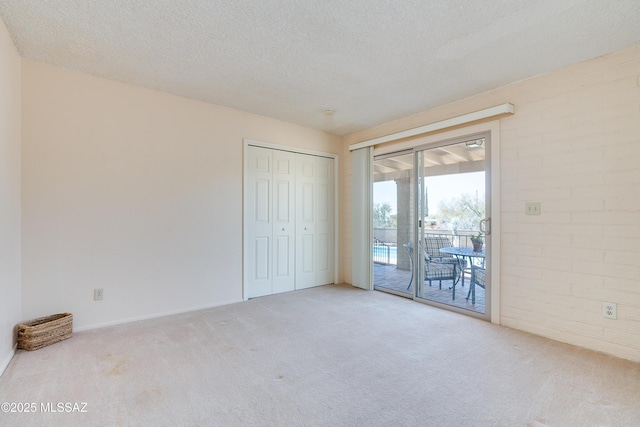 unfurnished bedroom with carpet floors, access to exterior, a closet, and a textured ceiling