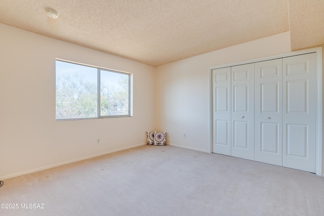 unfurnished bedroom with carpet, a closet, a textured ceiling, and baseboards