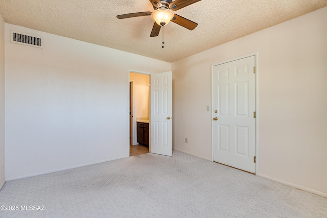 unfurnished bedroom with baseboards, visible vents, a textured ceiling, and light colored carpet