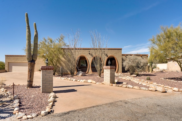 adobe home with a garage and concrete driveway