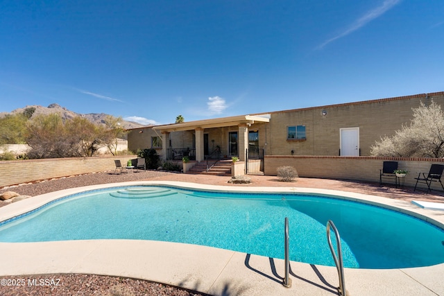 outdoor pool with fence, a mountain view, a diving board, and a patio