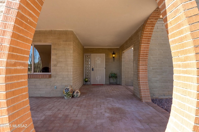 view of exterior entry featuring a patio area and brick siding