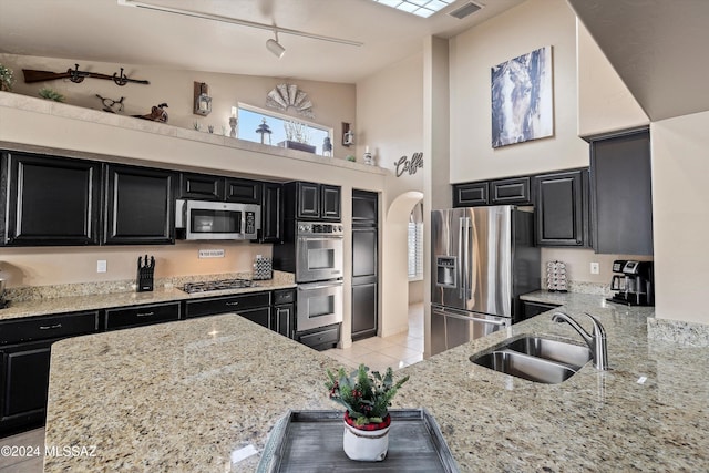 kitchen with appliances with stainless steel finishes, light stone counters, and sink