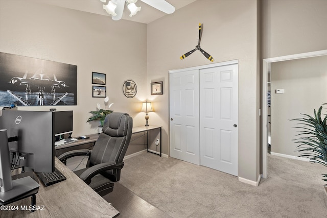 carpeted home office with ceiling fan and a towering ceiling