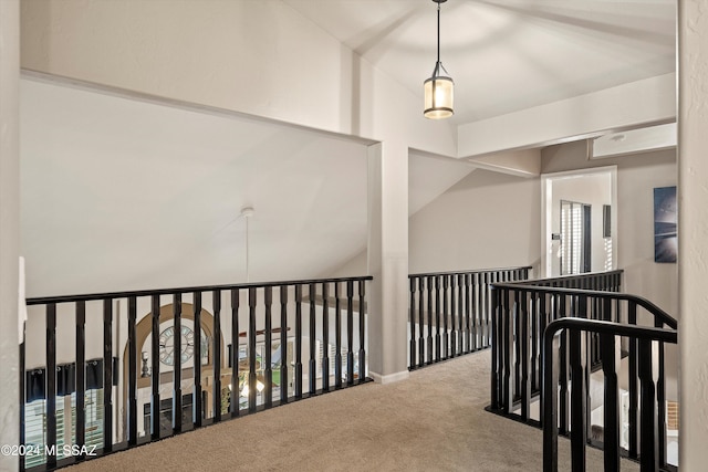 hallway with carpet floors and vaulted ceiling