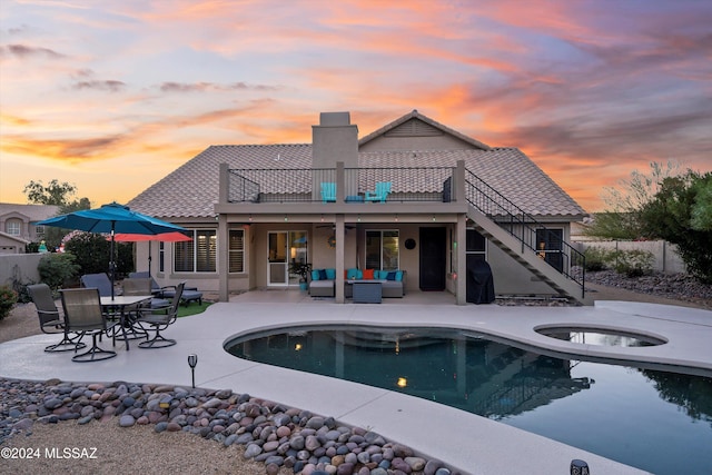 pool at dusk with outdoor lounge area, an in ground hot tub, and a patio area