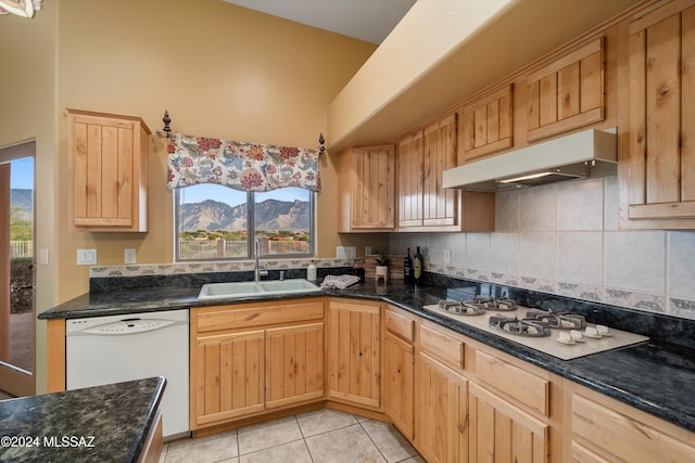 kitchen featuring sink, light brown cabinets, dark stone countertops, a mountain view, and white appliances