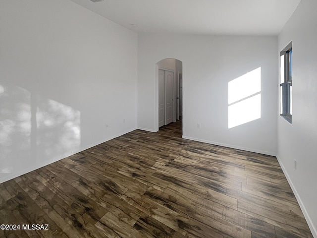 unfurnished room with dark hardwood / wood-style flooring and lofted ceiling