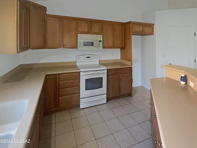 kitchen featuring light tile patterned flooring, white appliances, and sink